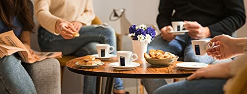 Group of people having coffee and pastries around a table.